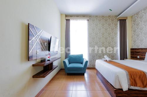 a bedroom with a bed and a blue chair at De Malang Sweet Homestay Syariah Mitra RedDoorz in Malang