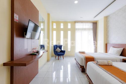 a hotel room with two beds and a tv at De Malang Sweet Homestay Syariah Mitra RedDoorz in Malang