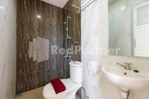 a bathroom with a shower and a toilet and a sink at De Malang Sweet Homestay Syariah Mitra RedDoorz in Malang