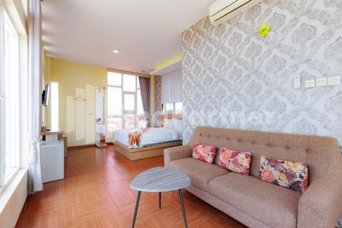 a living room with a couch and a bedroom at De Malang Sweet Homestay Syariah Mitra RedDoorz in Malang
