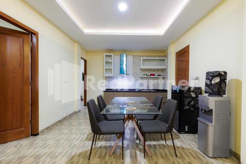 a dining room with a table and chairs and a kitchen at De Malang Sweet Homestay Syariah Mitra RedDoorz in Malang