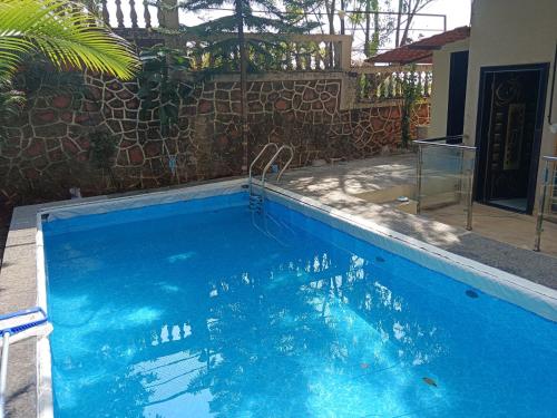 a large blue swimming pool in a yard at Malhar Bungalow in Panchgani