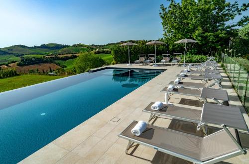 a row of lounge chairs next to a swimming pool at Relais Tenuta Santori in Cossignano