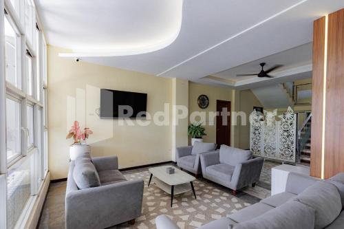 a living room with couches and a tv at De Malang Sweet Homestay Syariah Mitra RedDoorz in Malang