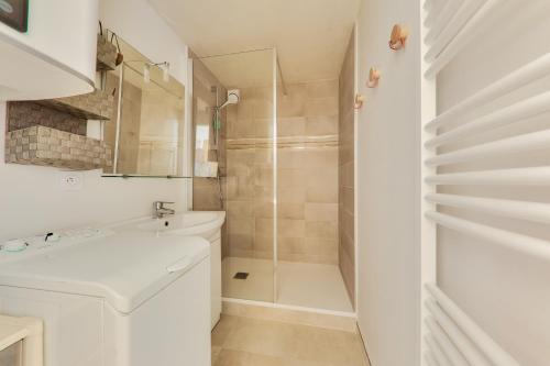 a white bathroom with a sink and a shower at Face à l'océan - Arzon - Appartement pour 4 in Arzon