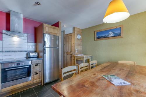 a kitchen with a wooden table and a refrigerator at Chalet le Regain in Villard-Reculas