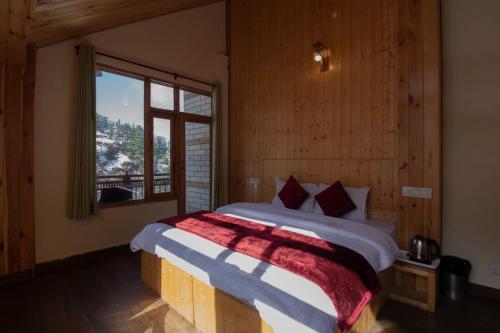 a bedroom with a large bed with a window at Crystal Mountain Jibhi in Jibhi