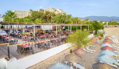 an outdoor patio with tables and chairs and a beach at Maya World Didyma Hotel in Didim