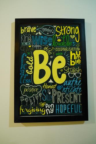 a framed painting of a be sign on a wall at Friends by Alizeh Bhagsunag McLeodganj in McLeod Ganj