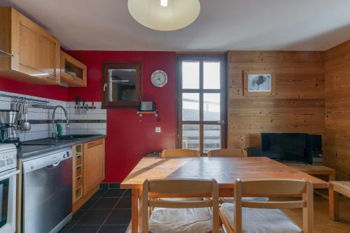 a kitchen with a wooden table and red walls at Chalet le Regain in Villard-Reculas