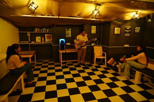 a man playing a guitar in a room with people at Friends by Alizeh Bhagsunag McLeodganj in McLeod Ganj