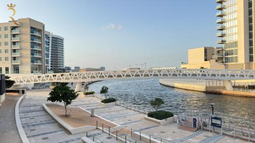 a bridge over a river in a city with buildings at Luxury 2BR Living in Al Rahah - Elegant Stay Near Al Raha Beach & Marina in Abu Dhabi