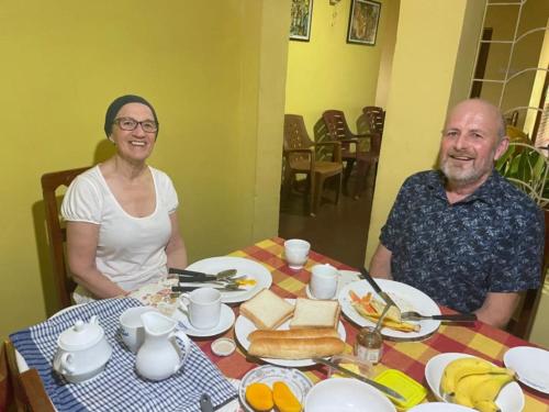 a man and a woman sitting at a table with food at Olivia HomeStay in Anuradhapura