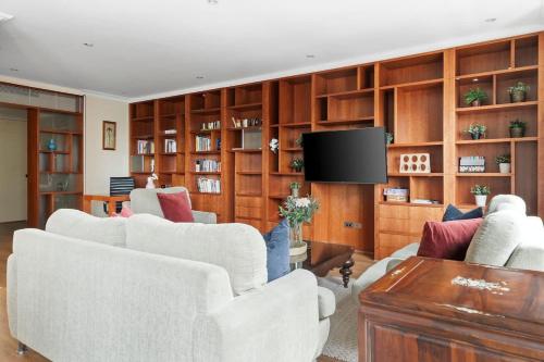 a living room with white furniture and wooden cabinets at Stylish & Cozy 4BR Retreat with FREE Parking in Melbourne