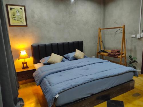 a bedroom with a large bed with a blue comforter at Phudis Guest House in Ban Khlong Haeng