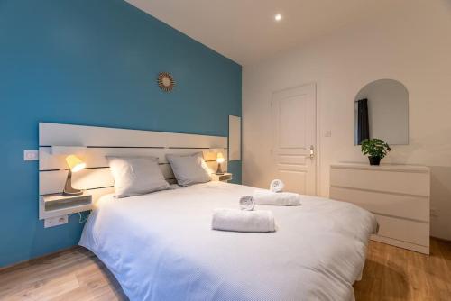 a bedroom with a large white bed with a blue wall at L'appart du Général in Elbeuf
