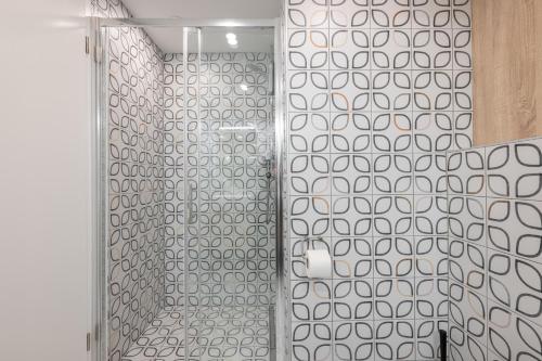 a bathroom with a shower with white and gray tiles at Mandina Studios on a main Square in Zagreb