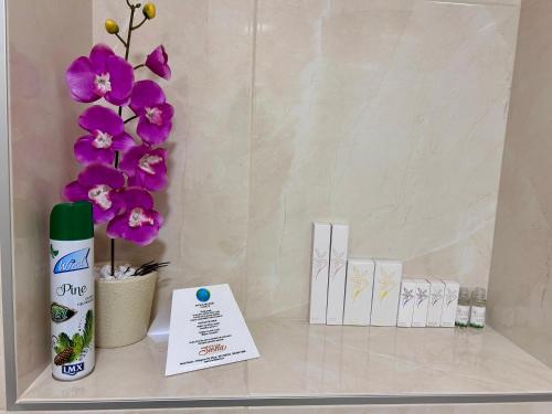 a shelf with a bottle of lotion and purple flowers at Hotel Siesta in Užice