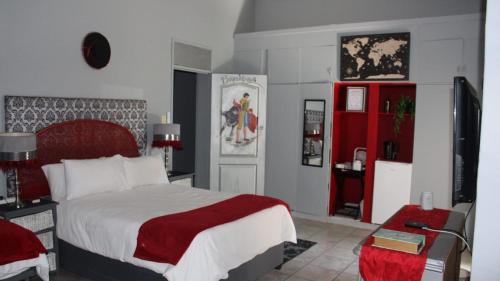 a bedroom with a large bed with a red and white blanket at Eagle's Nest in Barberton