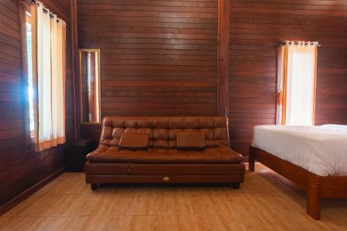 a leather couch in a room with a bed at Pondok Hari Baik in Balian