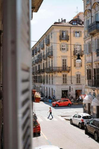 a person walking down a city street with cars at Tomato Urban Retreat in Turin