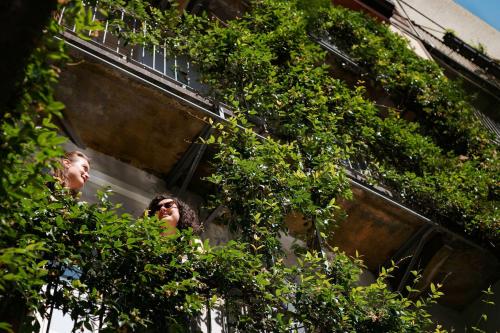 two women looking out of a building through trees at Tomato Urban Retreat in Turin