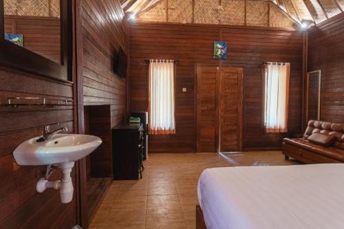 a bathroom with a sink and a bed in a room at Pondok Hari Baik in Balian