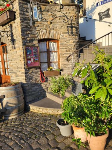 a stone building with potted plants in front of a door at Hotel Restaurant Alte Stadtmauer in Beilstein
