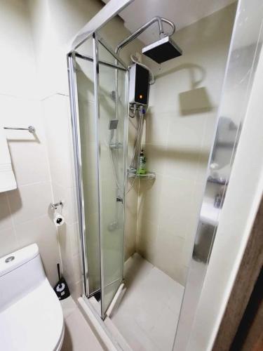a bathroom with a shower and a toilet with a glass door at Mavic Staycation in Manila