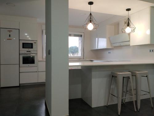 a kitchen with white cabinets and bar stools at Abril 56 Villa&Suites in Oreña