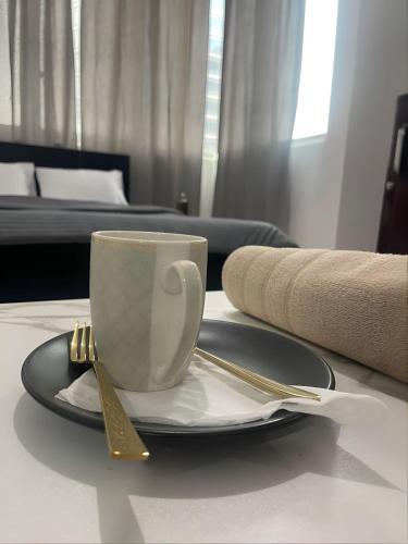 a coffee cup on a table with a fork and knife at Sea View Stay Abu Dhabi in Abu Dhabi