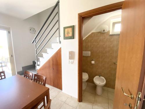 a bathroom with a toilet and a staircase with a table at Isca Calabretta Apartments M28 in Isca sullo Ionio