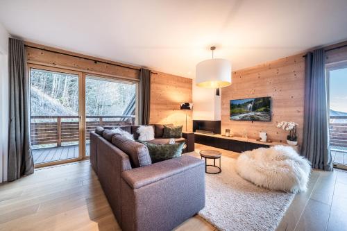 un salon avec un canapé et une grande fenêtre dans l'établissement Maira Les Carroz - by EMERALD STAY, à Arâches-la-Frasse