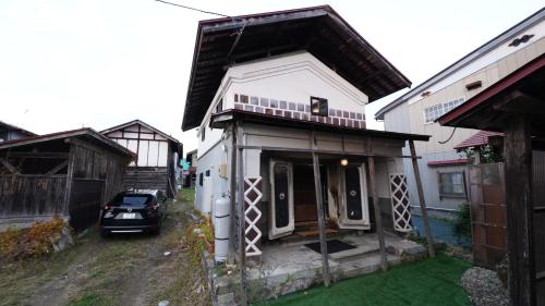 a house with a car parked in front of it at Kominka Hotel FUKUNOKURA 古民家ホテル ふくの蔵 #FR1 in Nishiaizu