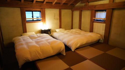 a room with two beds in a room with a checkered floor at Kominka Hotel FUKUNOKURA 古民家ホテル ふくの蔵 #FR1 in Nishiaizu