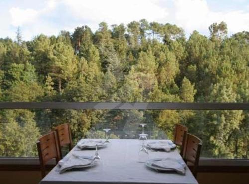 a table on a balcony with a view of a forest at Hotel O´xardin in Carballino