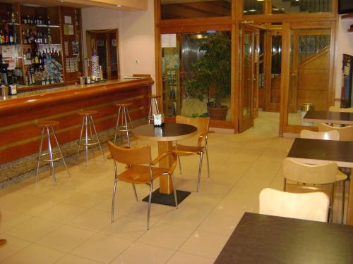 a restaurant with tables and chairs and a bar at Hotel O´xardin in Carballino
