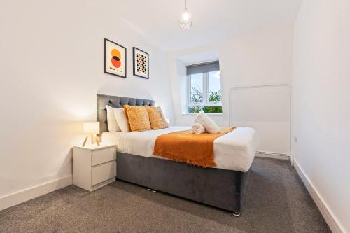 a bedroom with a king sized bed with an orange blanket at Stylish Two Bedroom Apartment - Secure Parking & Balcony 9MC in Birmingham