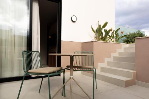 two chairs and a table on a balcony with stairs at M31Boutique Suites in Mellieħa