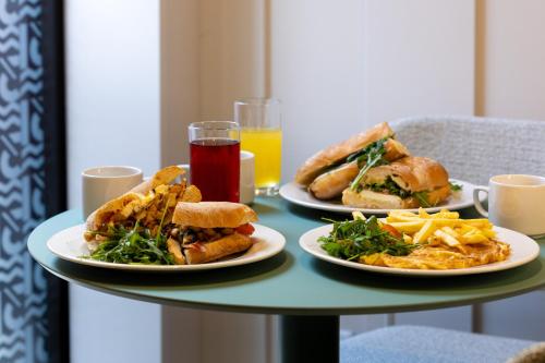 two plates of food on a table with sandwiches and french fries at M31Boutique Suites in Mellieħa