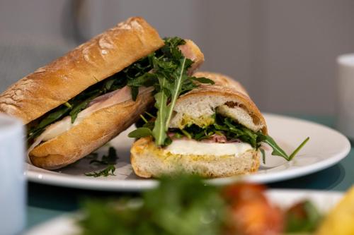 a sandwich is cut in half on a white plate at M31Boutique Suites in Mellieħa