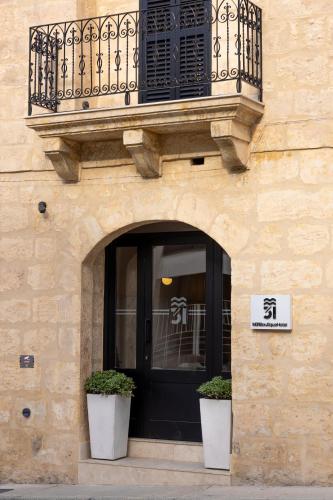 a building with two potted plants in front of a door at M31Boutique Suites in Mellieħa