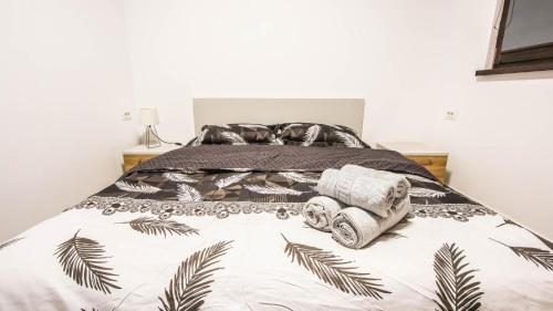 ein Bett mit einer schwarzen und weißen Bettdecke und Handtüchern in der Unterkunft Panoramic de lux Mihai Bravu cu internet de mare viteza si parcare gratuit in Bukarest