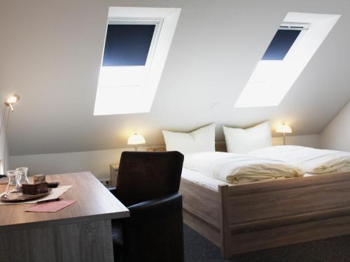 a bedroom with a bed and a table with a chair at Hotel Zum Großen Krug in Wirdum