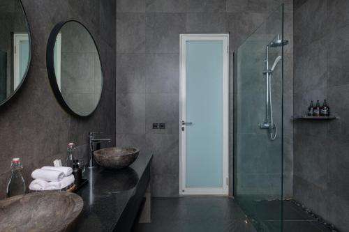 a bathroom with a sink and a shower with a mirror at Villa Levi by GORO in Seminyak