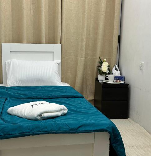a bed with a blue blanket and a white pillow at Amazing Sea View Stay Abu Dhabi in Abu Dhabi