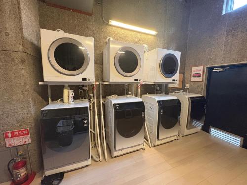 a group of four washers and dryers lined up against a wall at Peace INN HAGI in Hagi