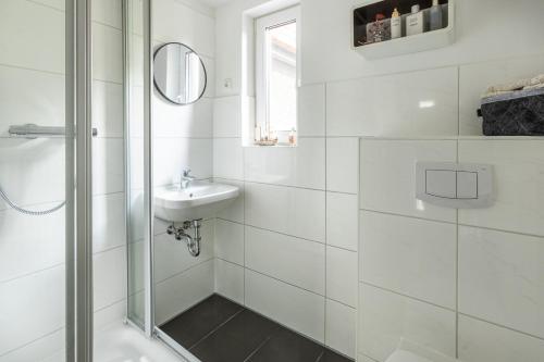 a white bathroom with a sink and a shower at Duvenstedter Rotklinker in Hamburg