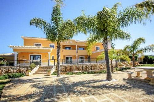 a large yellow building with palm trees in front of it at Quinta do Sol in Guia