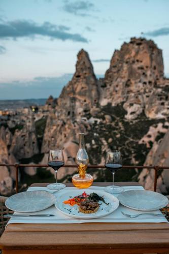 a table with a plate of food and wine glasses at Via Regia Cappadocia Hotel in Uchisar